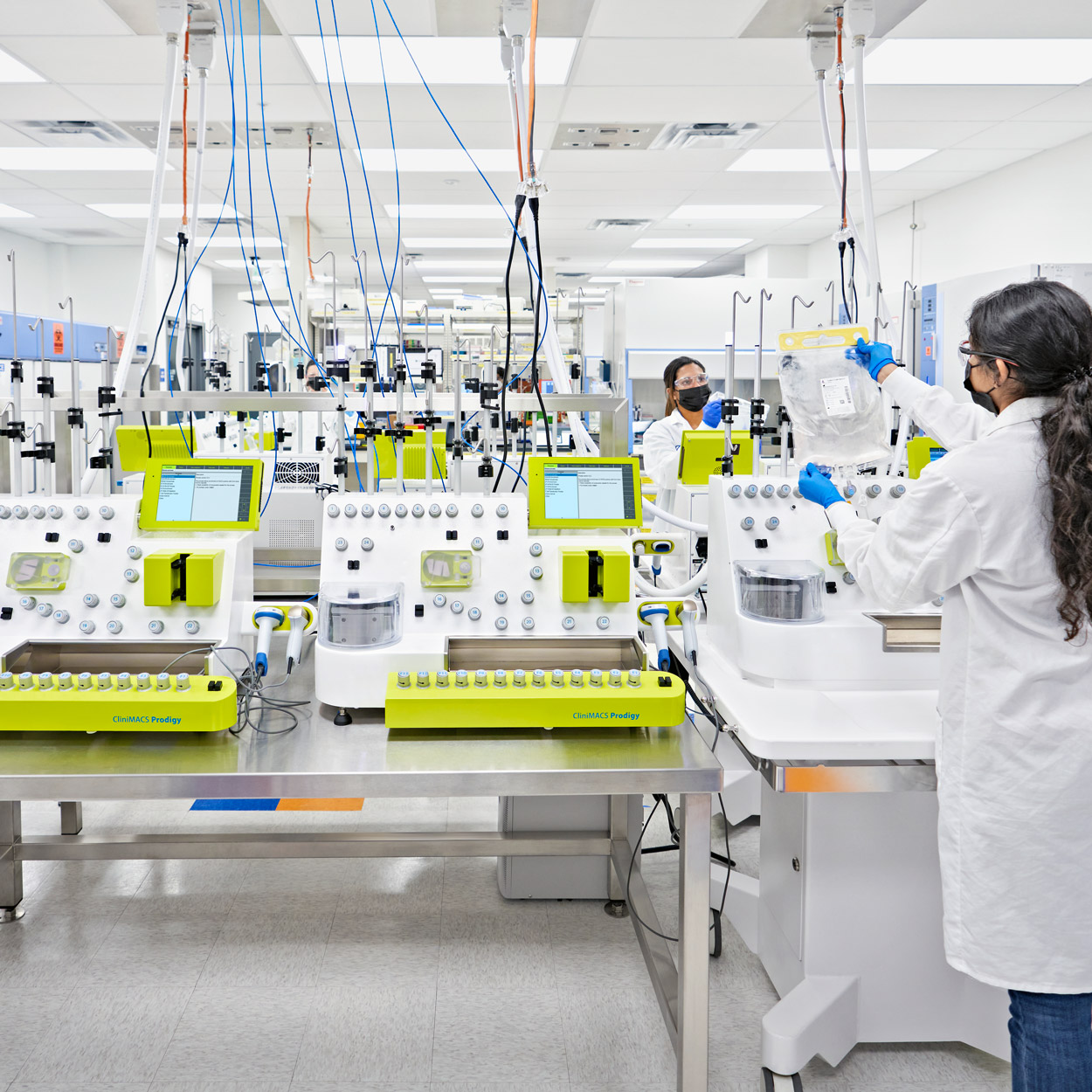 Two females in lab attire setting up rows of CliniMACS Prodigies.